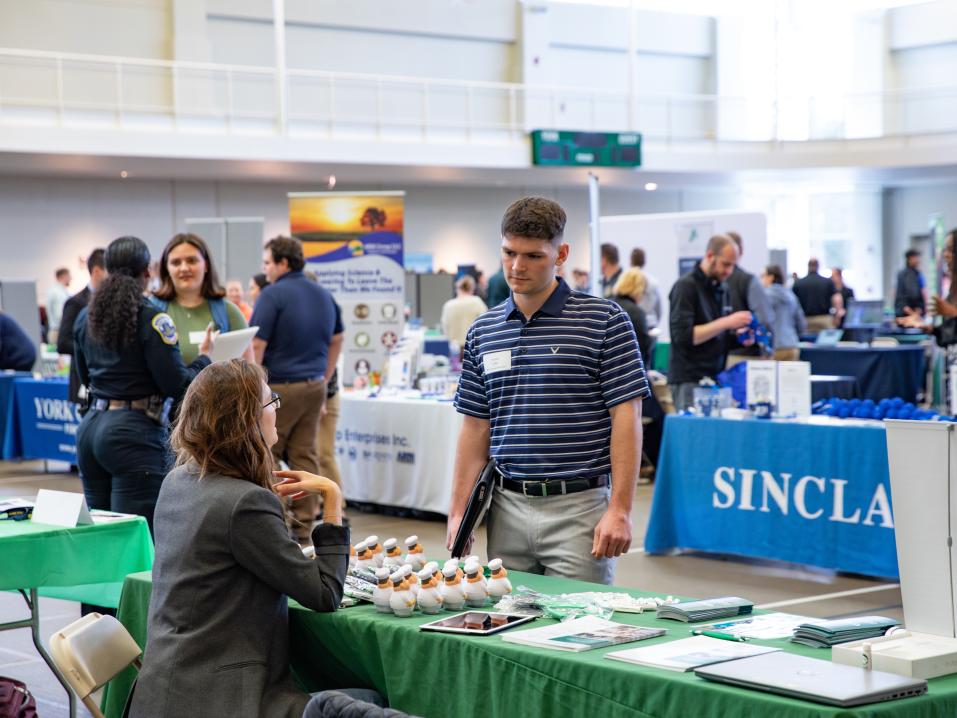 Student talks to a recruiter at a career fair booth