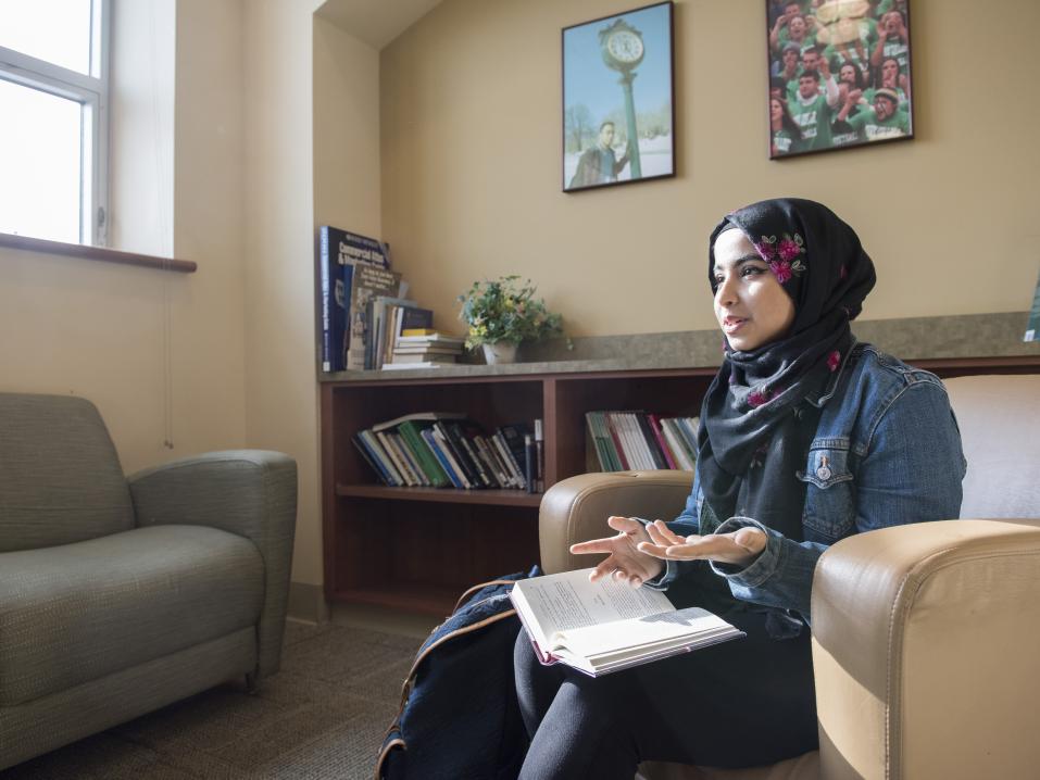 Student reads a book sitting in a chair in a library 