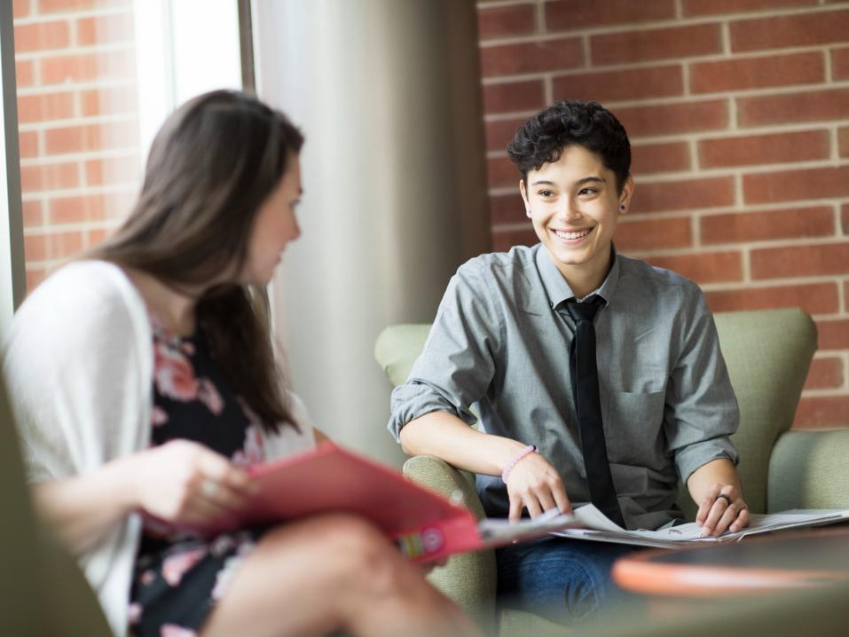 Two smiling students sitting indoors