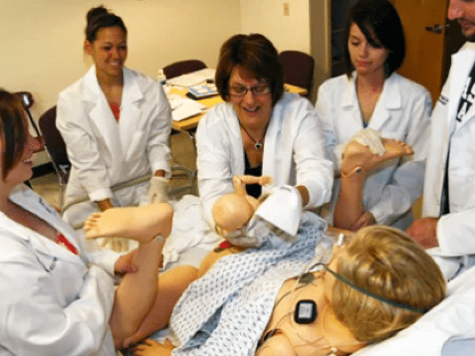 The birth simulator giving birth while students help.