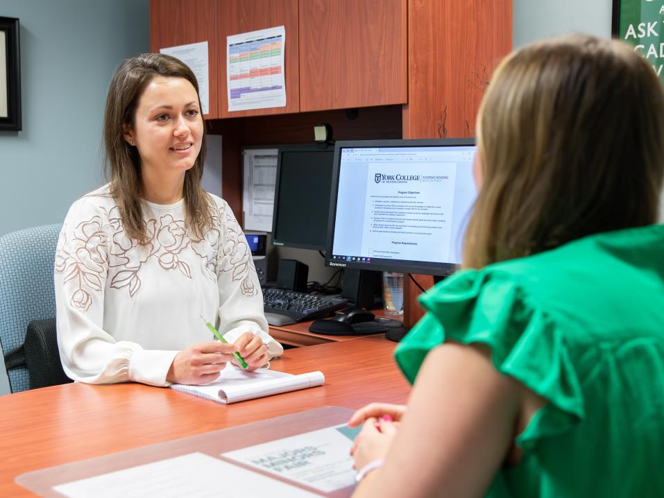 An advisor meets with a student in her office.