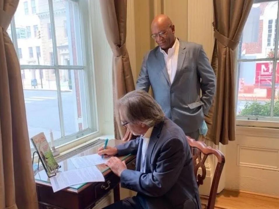 Dominic DelliCarpini signing a letter in a historical center.