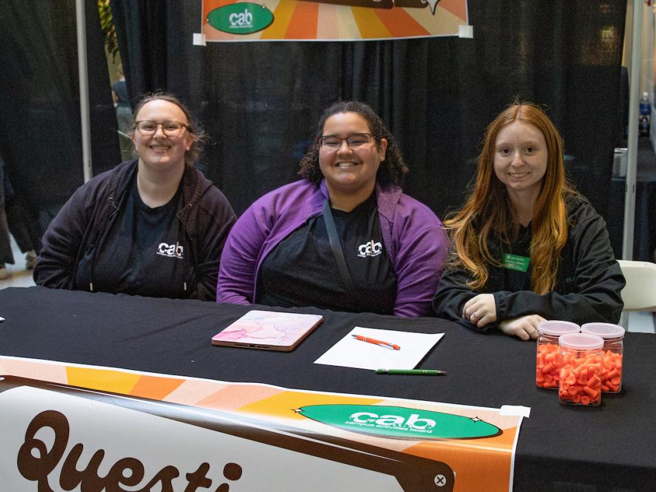 Three students sit at the "Questions Table" at the spring concert in the field house.