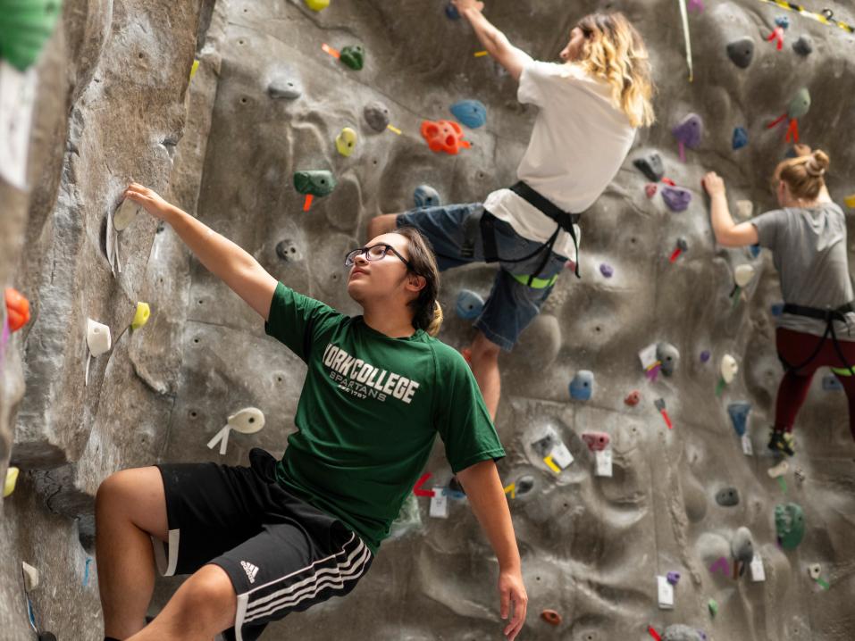 Students climb the rock wall.