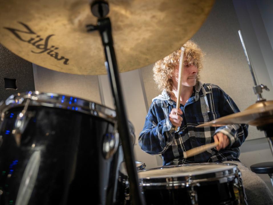 A student in the York College Rock Band plays the drums.