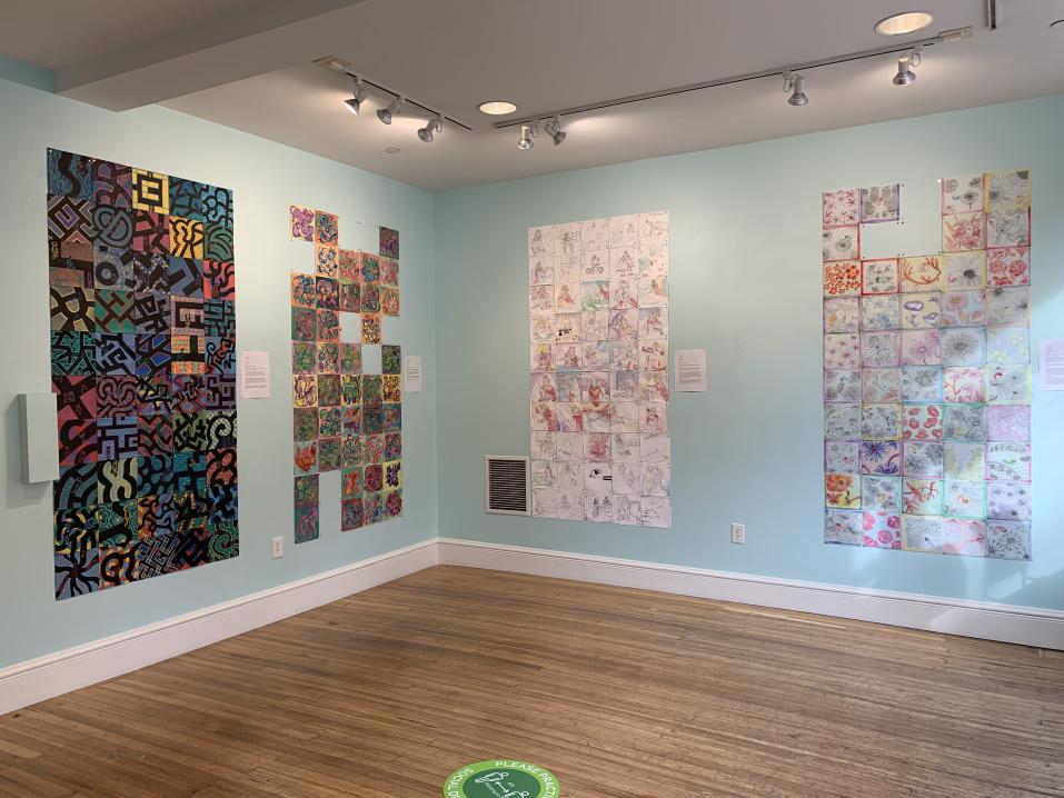 Nearly 200 small paintings and drawings by YCP Fine Art students displayed on blue walls.