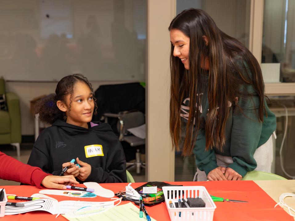 A student and child work together with paper and markers