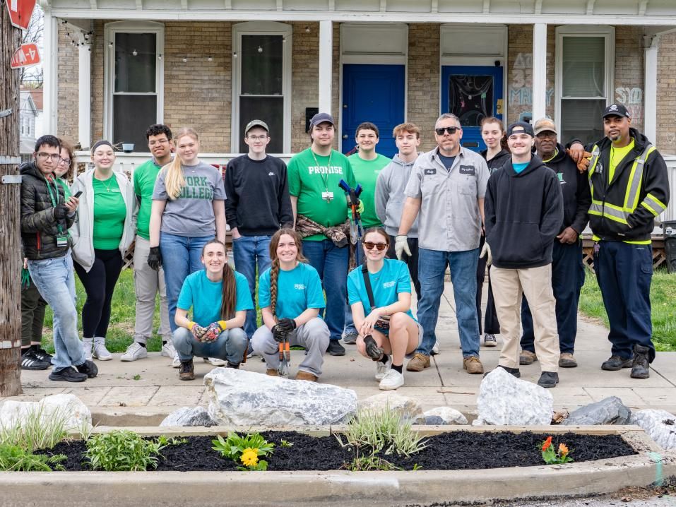 A group of students pose together for a photo with a garden on Jackson Street