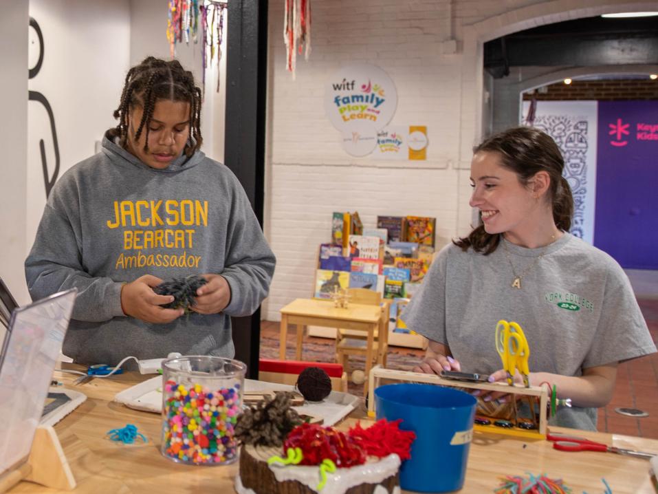 Student Ava German works on a craft at a table with another person