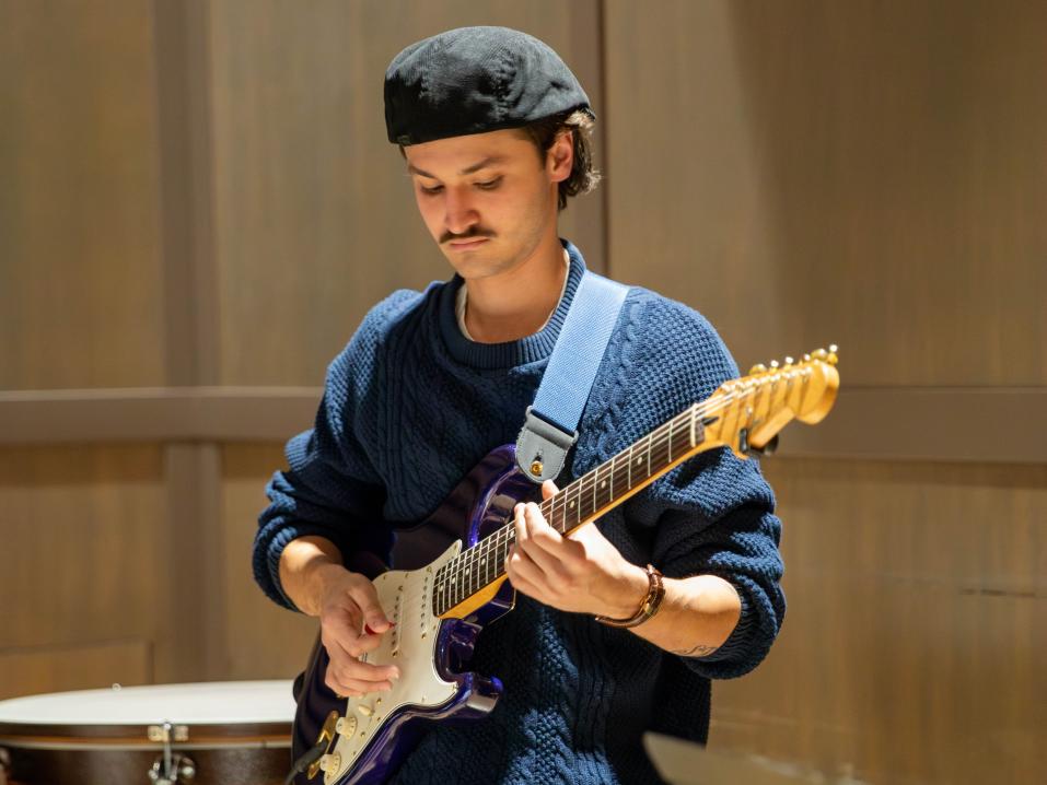 A student plays guitar in a theater.