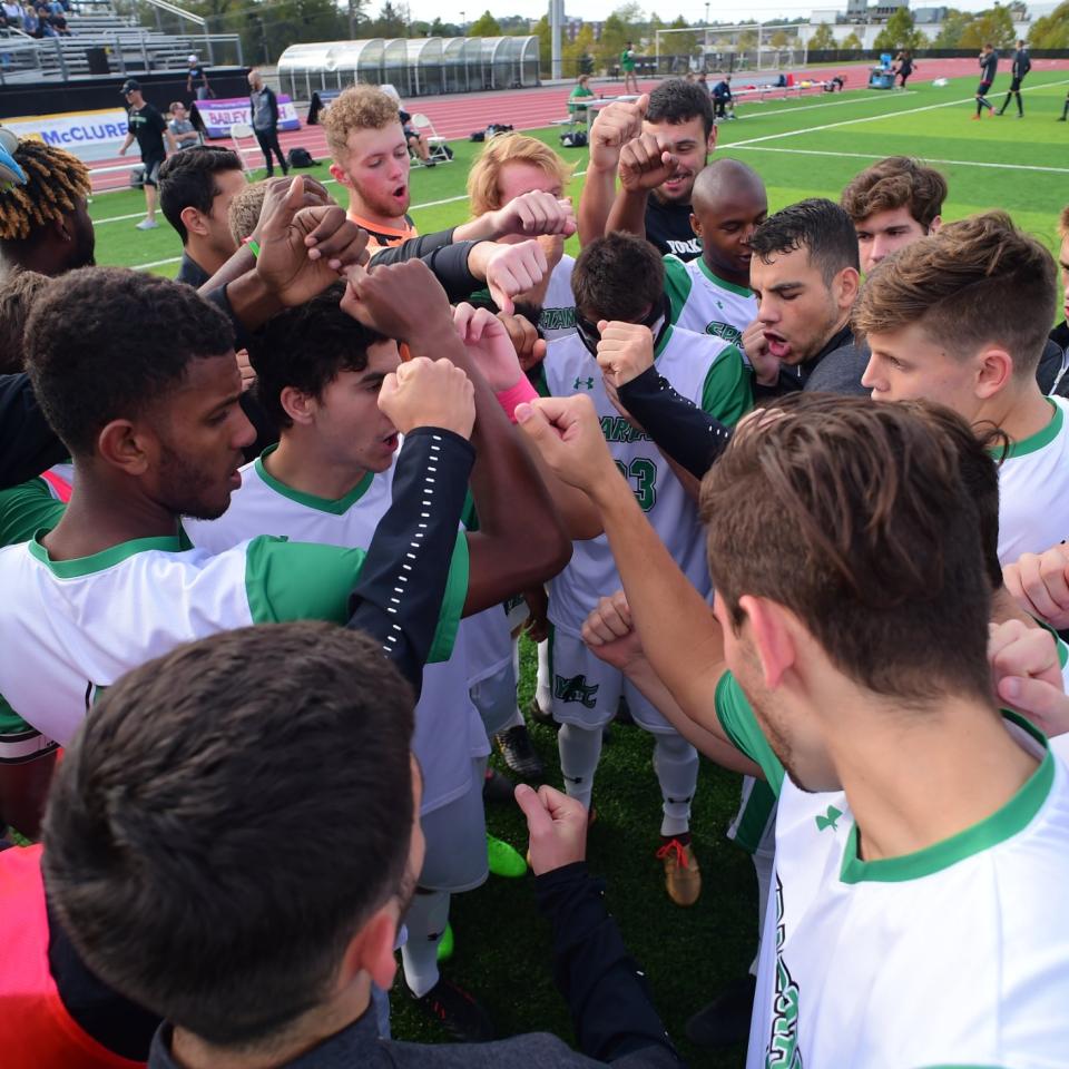 Athletics team huddles together with hands together on field