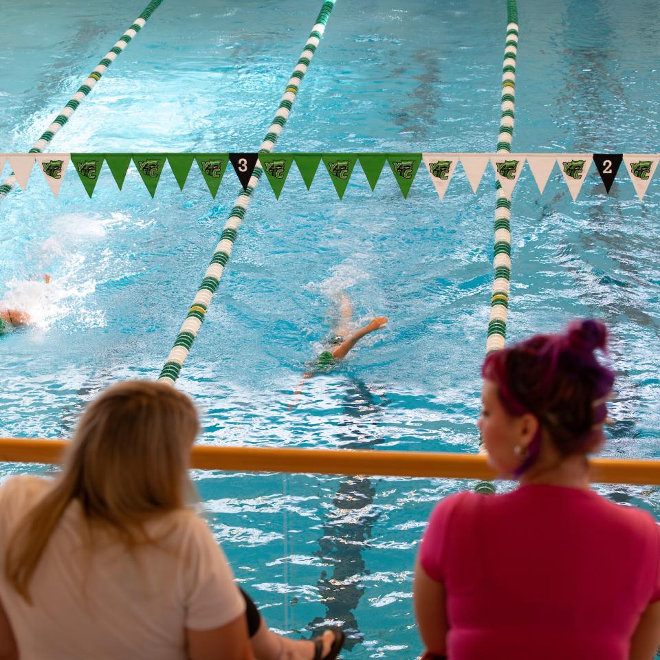 Two spectators look toward the pool during a swimming competition.