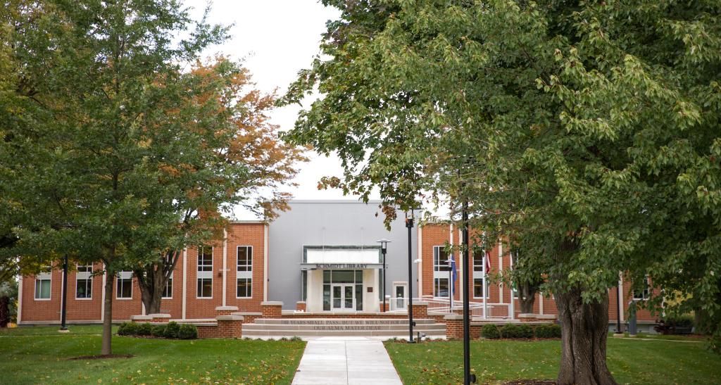 The front of the Schmidt Library faces the campus quad, full of trees and greenery.