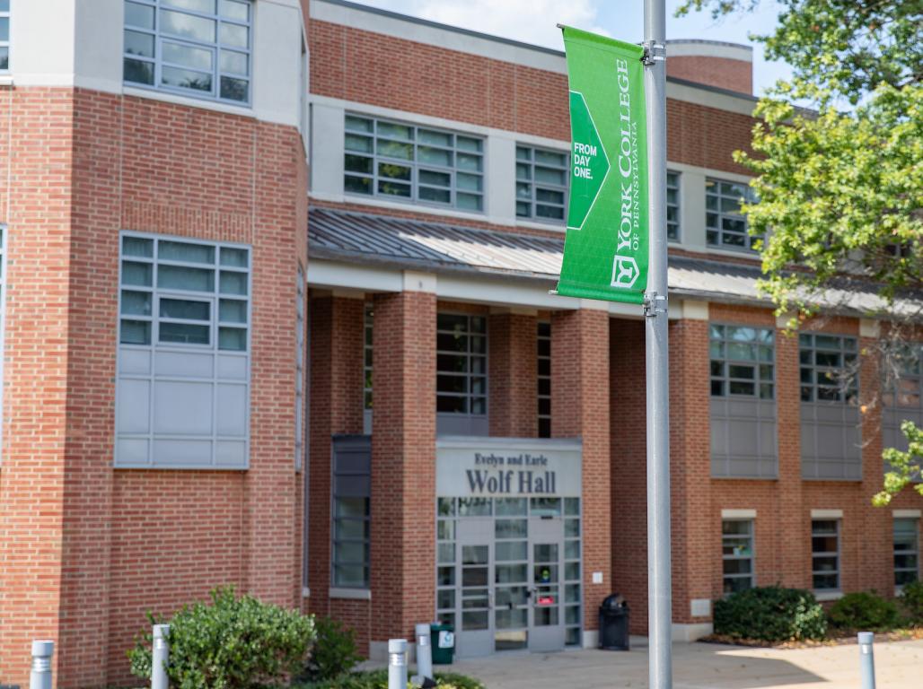 An exterior photo of Wolf Hall with a focus on the YCP banner outside of the building.