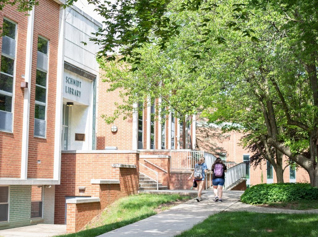 Students walk across campus, past the library.