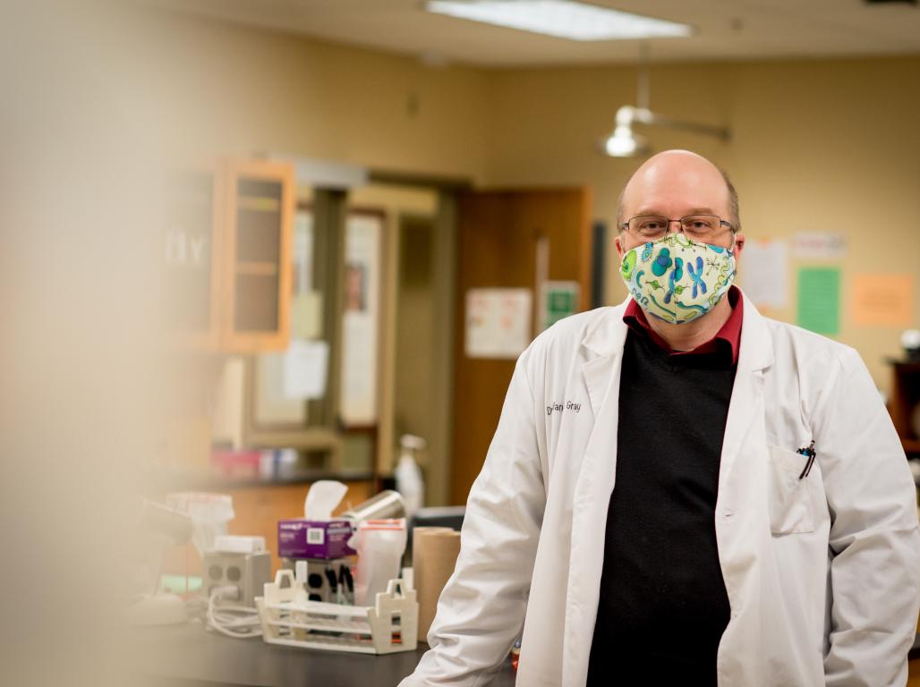 Brian Gray standing in lab with mask on 