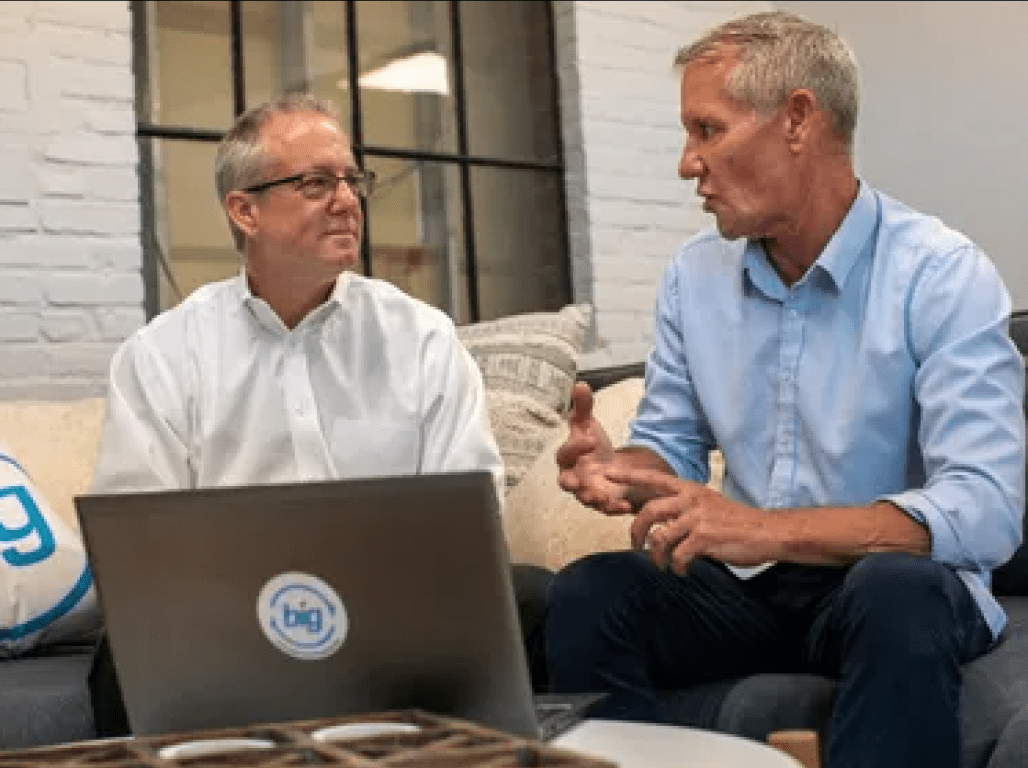 John and Scott Dometsch chat while looking at a laptop.