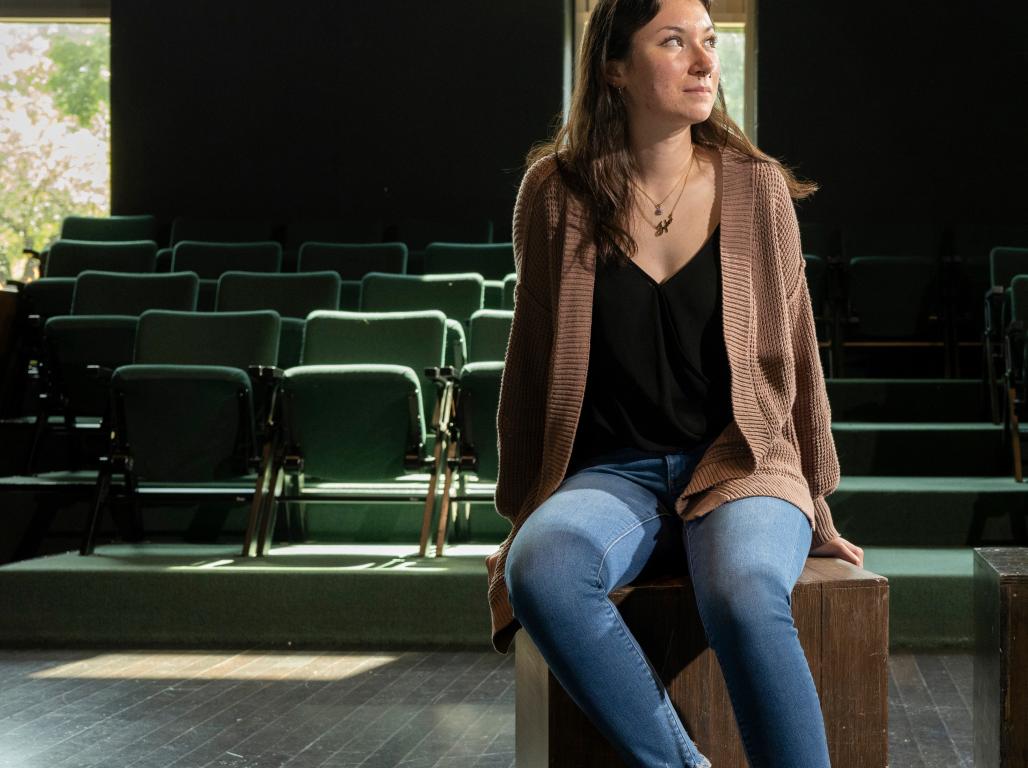 Eva Heier poses sitting on a bench look up and to the right of the viewer.