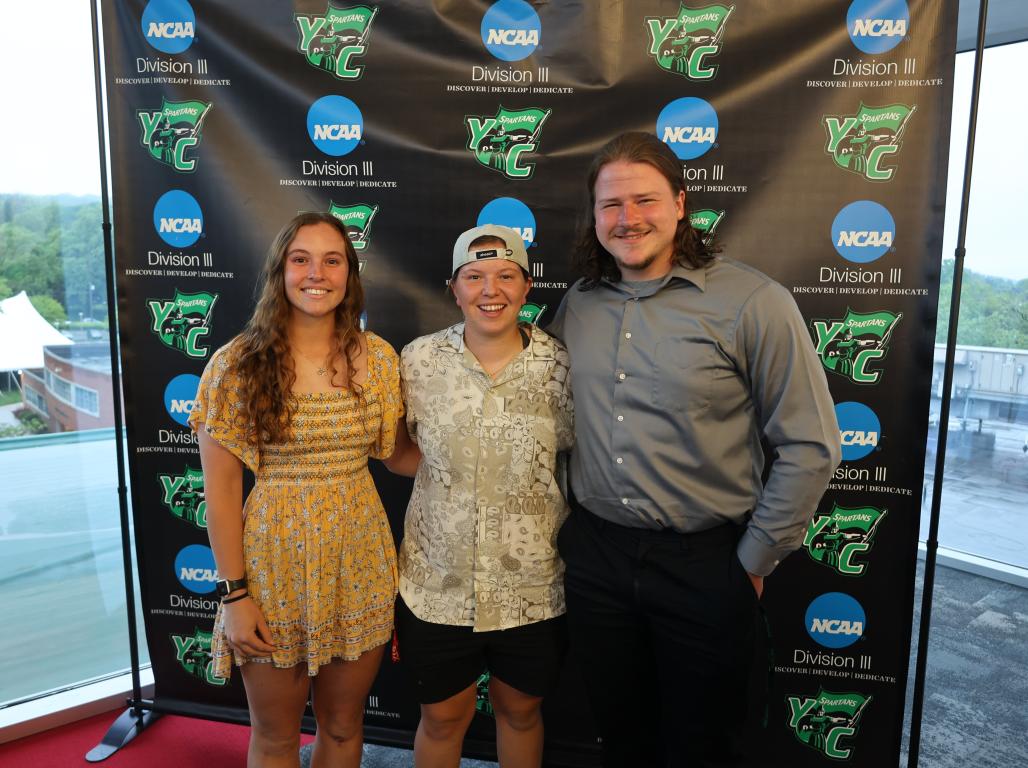 3 spartan athletes in front of a background getting their photo taken.