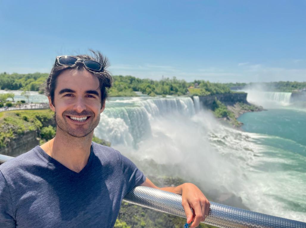 Francisco leaning against a railing in front of the Niagara Falls.