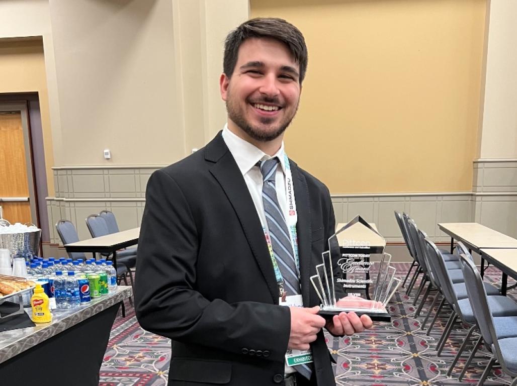 Gilbert Vial poses holding an award in a meeting room.