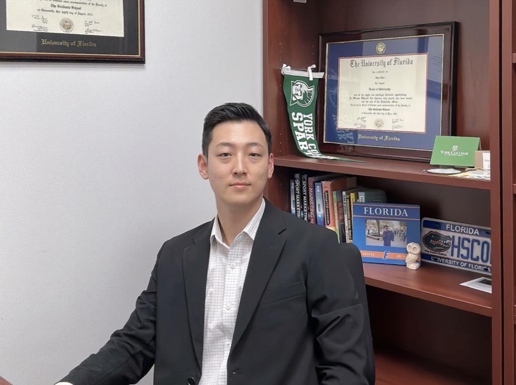 Inje Cho poses in his office, seated behind his desk