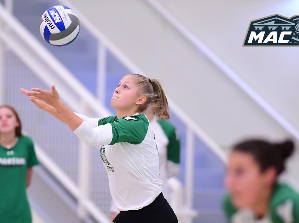 Abby Diehl jumps with hands outstretched to intercept a volleyball heading towards her.