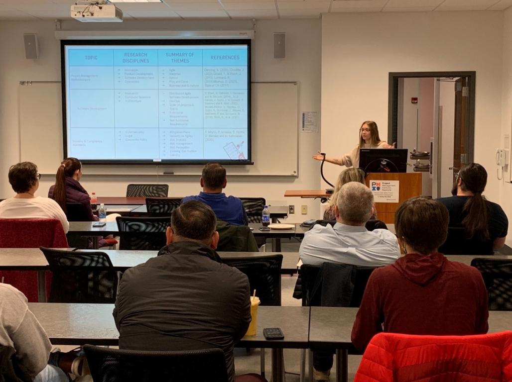 Natilie Mccallick presents her senior thesis standing at a podium with movie screen behind her.