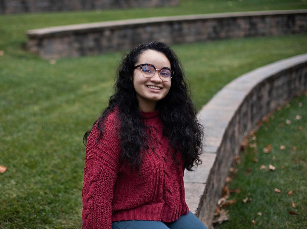 Alexis Rivera sitting in the campus ampitheater.