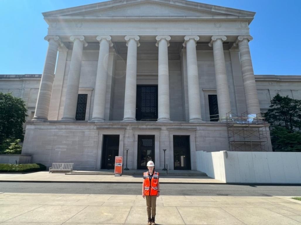 Zoe Klugel stands in front of a large stone building featuring tall columns above the entranceway.