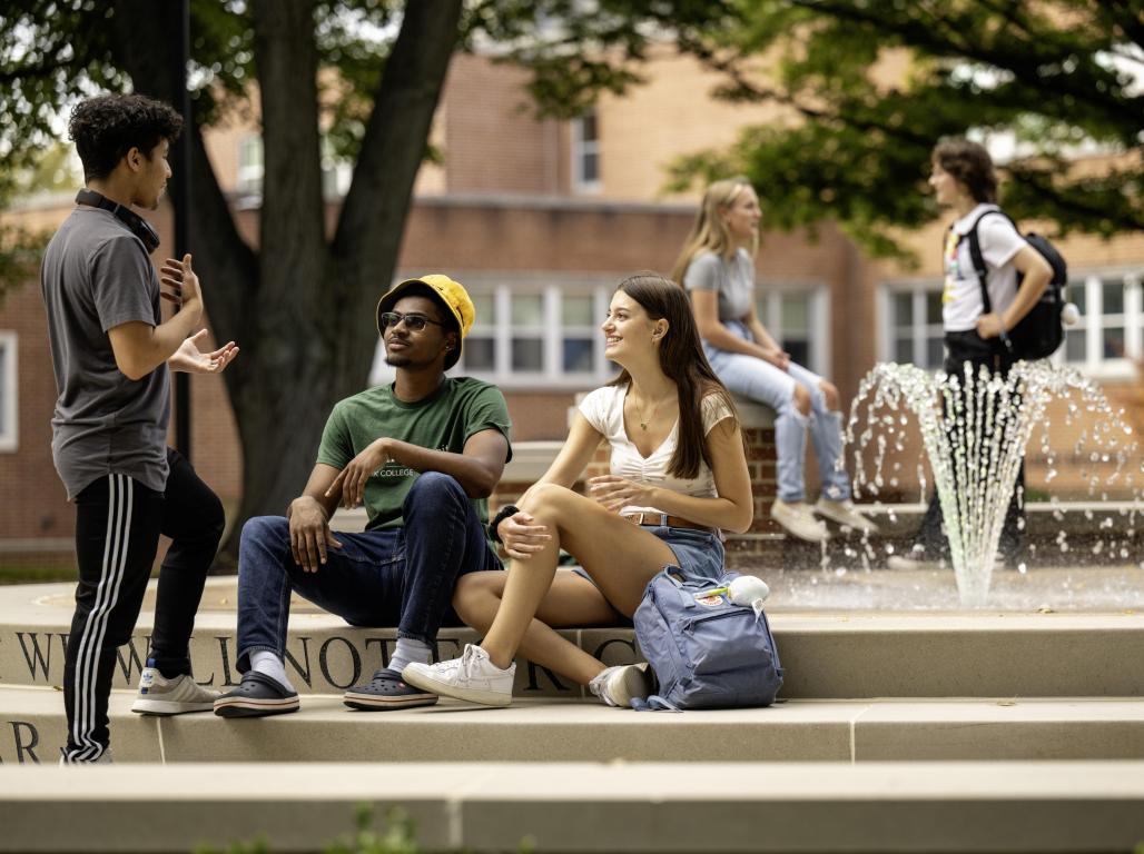 Students sitting on the fountain steps, smiling, mid-conversation.