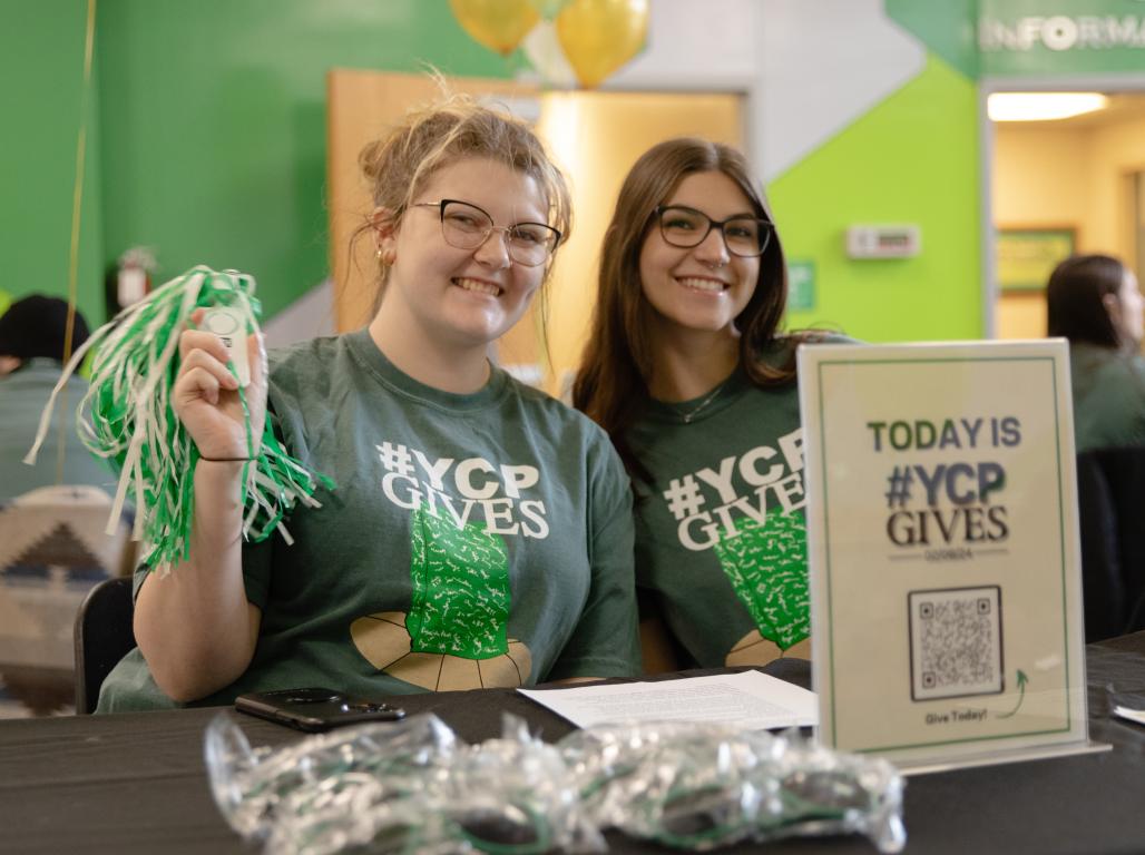 Two students sit together smiling at YCPGives event