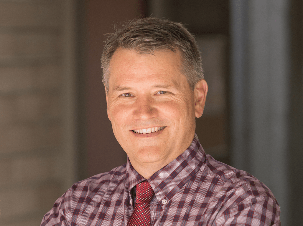Person smiling at the camera wearing a red tie and collared shirt.