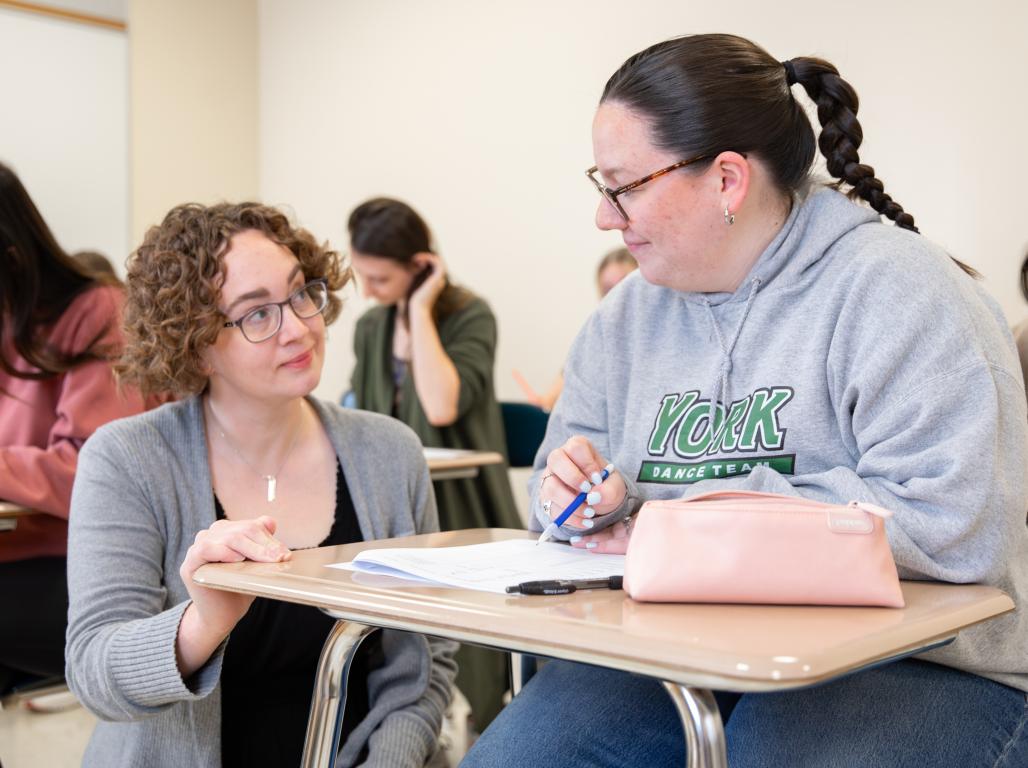 Dr. Samantha Deffler talks to a student at her desk