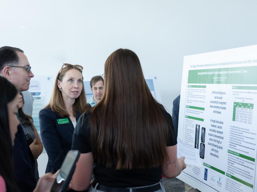 A student stands next to their presentation for the Undergraduate Research Showcase along with Dr. Burns and Dr. Sauder