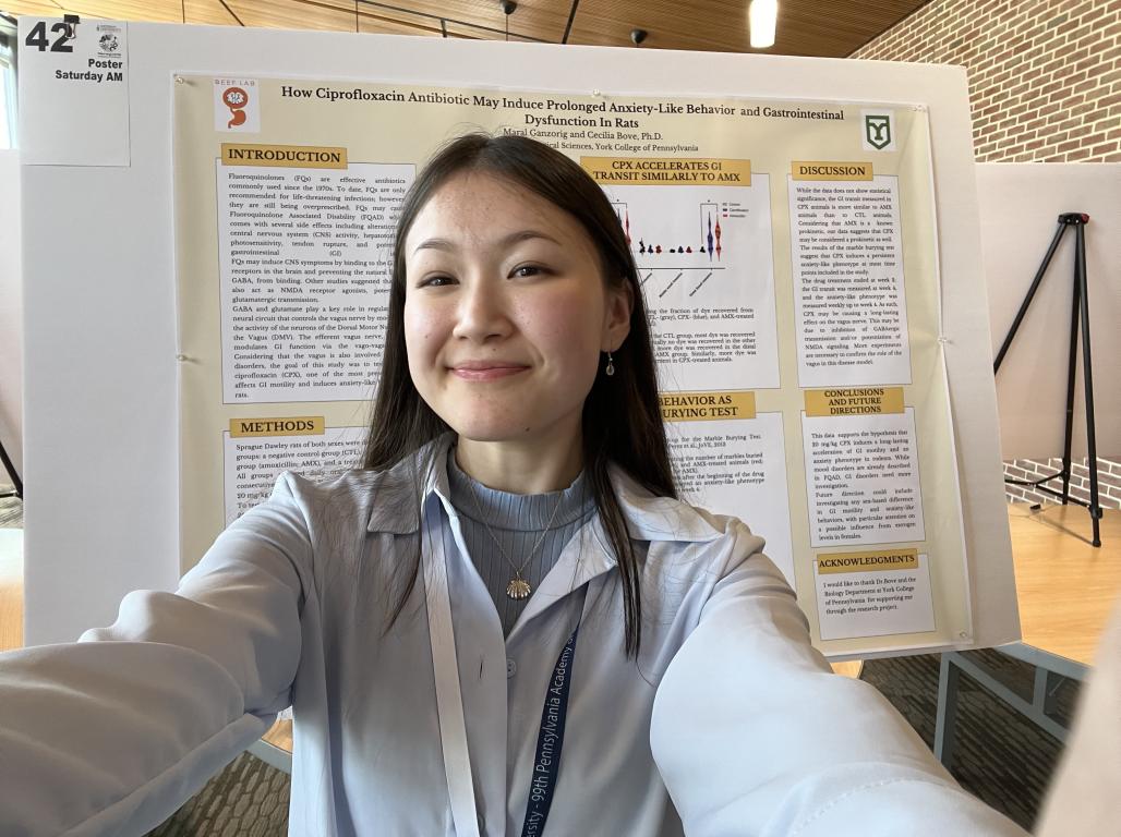 Selfie of a student in front of their science research poster.