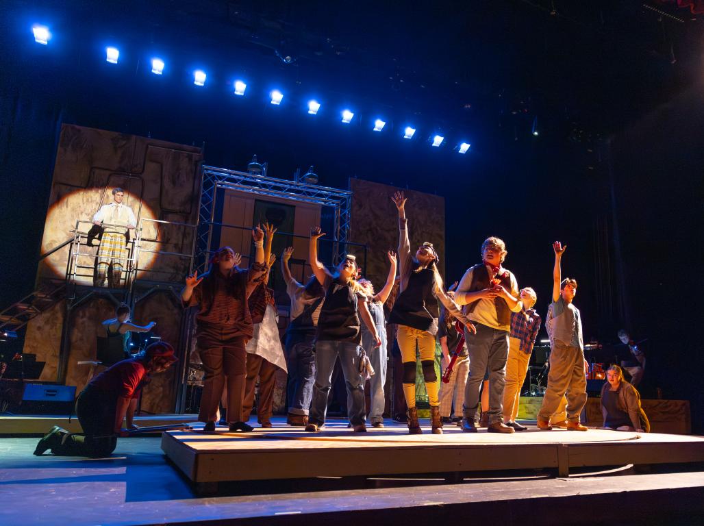 A group of performers on the stage with their hands raised in the air. 