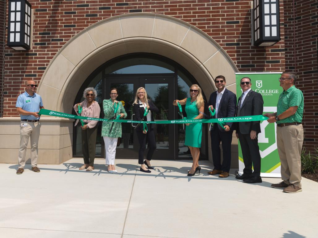 Group of people cutting a green ribbon outside Northside Commons at York College of Pennsylvania