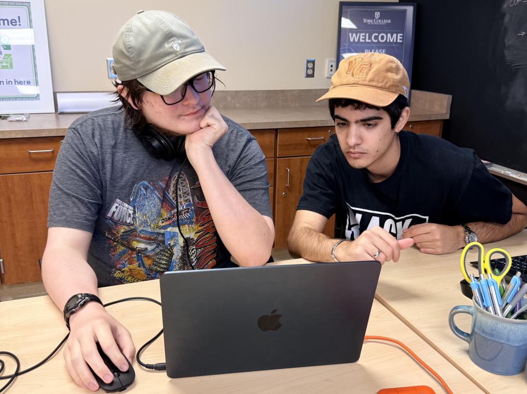 Two students together at a laptop.