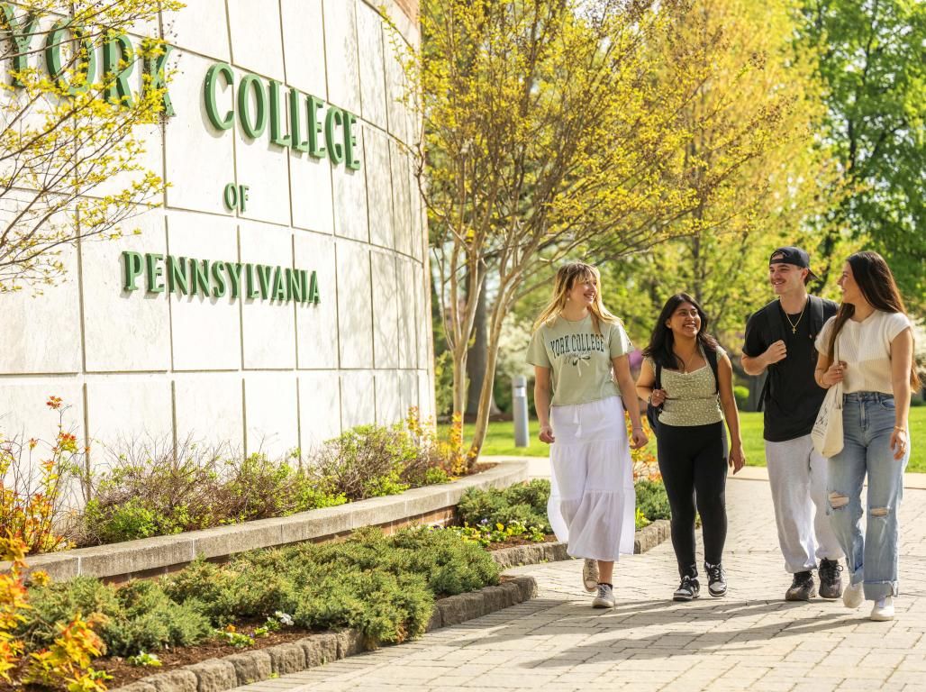A group of YCP students walking in front of a York College sign.