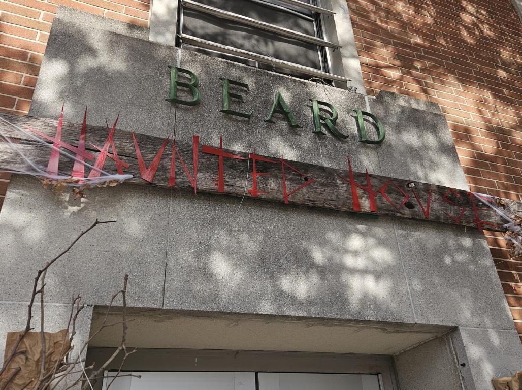 A handmade “Haunted House” sign with fake cobwebs hangs above the entrance to Beard Hall.