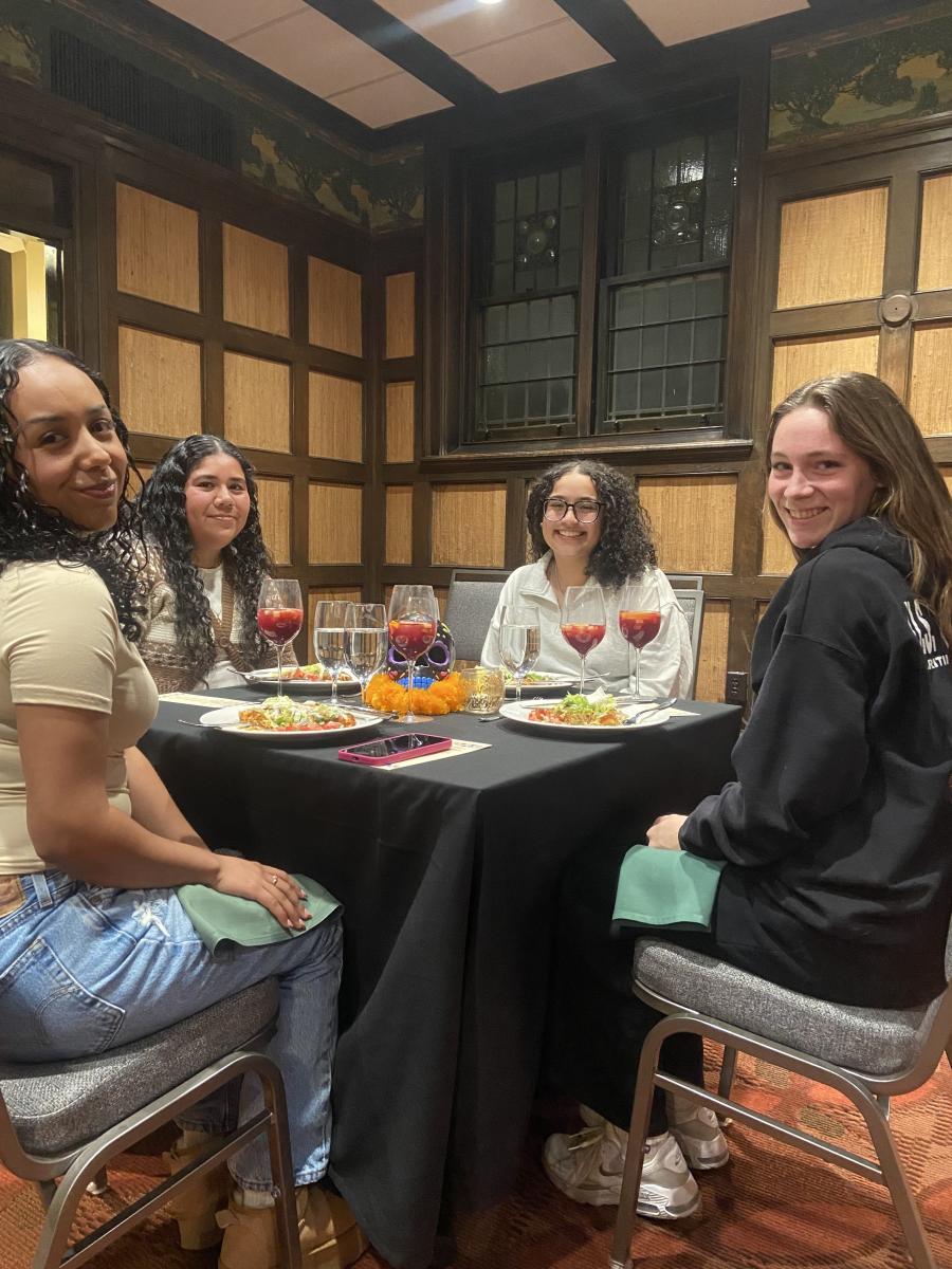 Students smile at the camera while seated for dinner.