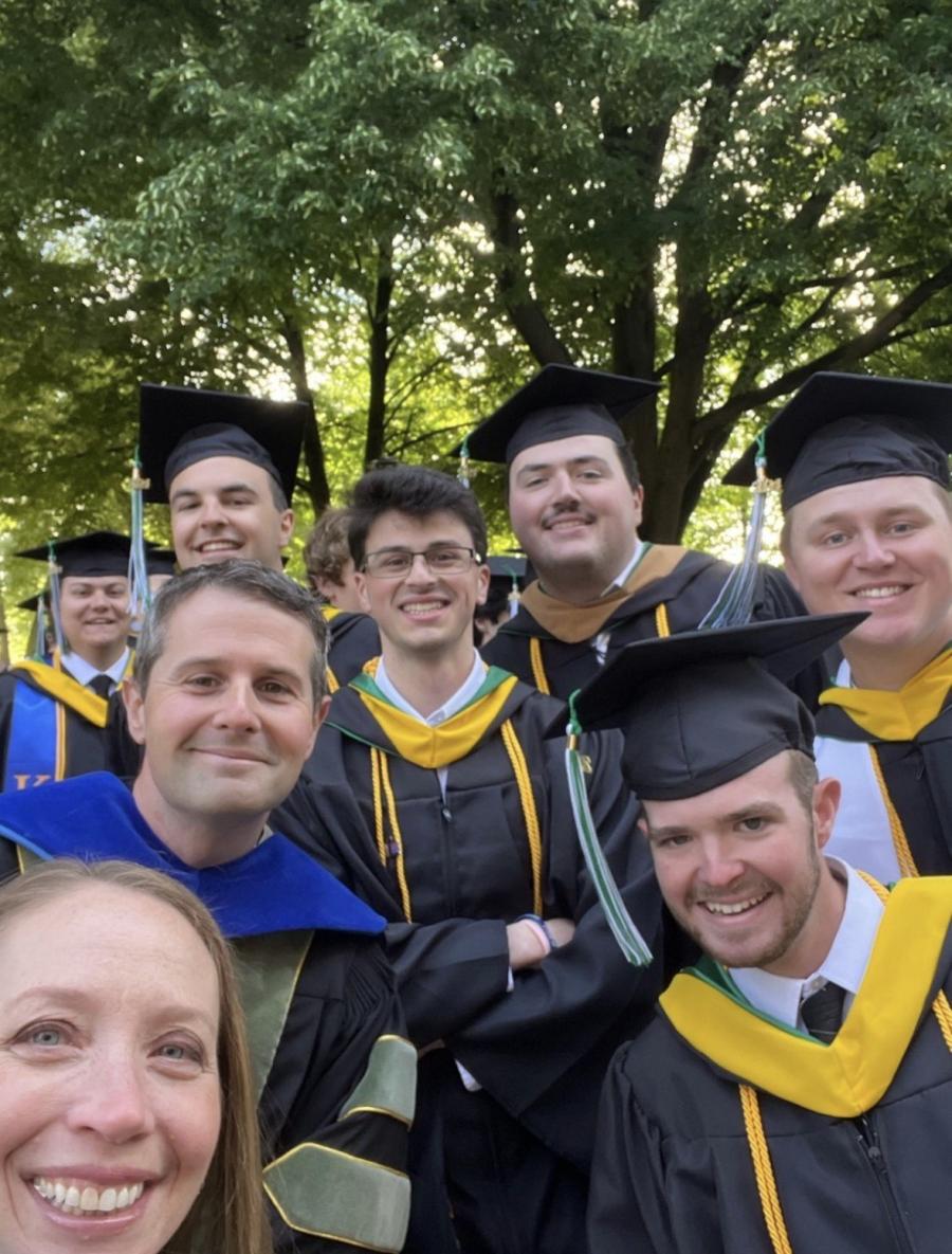 A group of YCP grads in regalia posing for a selfie with Dean Molly Sauders.