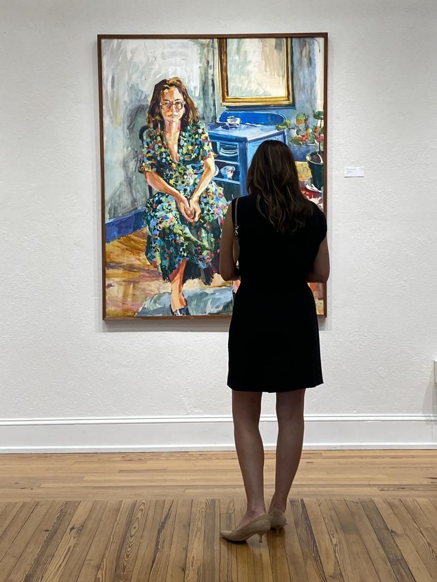 A visitor stands in front of a large portrait painting displayed on a white gallery wall at Marketview Arts.