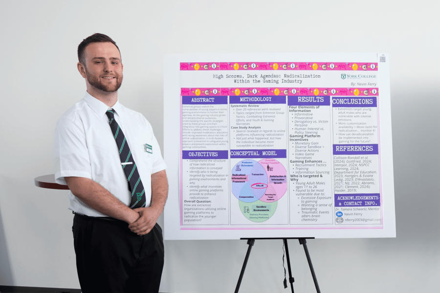 Nevin Ferry ’25 stands beside his research poster, “High Scores, Dark Agendas: Radicalization Within the Gaming Industry,” which presents findings on extremist recruitment and online gaming environments.