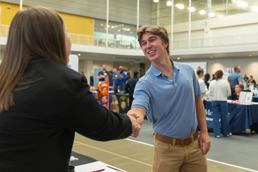 A student at the career expo shaking hands with someone.
