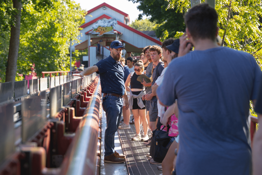 A Hersheypark engineer speaks with York College Civil Engineering students beside a roller coaster track during a behind-the-scenes tour.