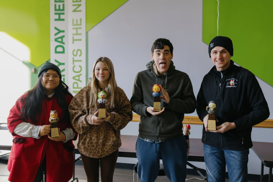 Four York College students smile while holding Haunted House award trophies.