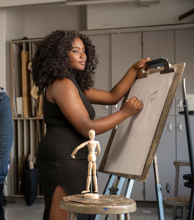 Two students in an art class drawing on canvas.