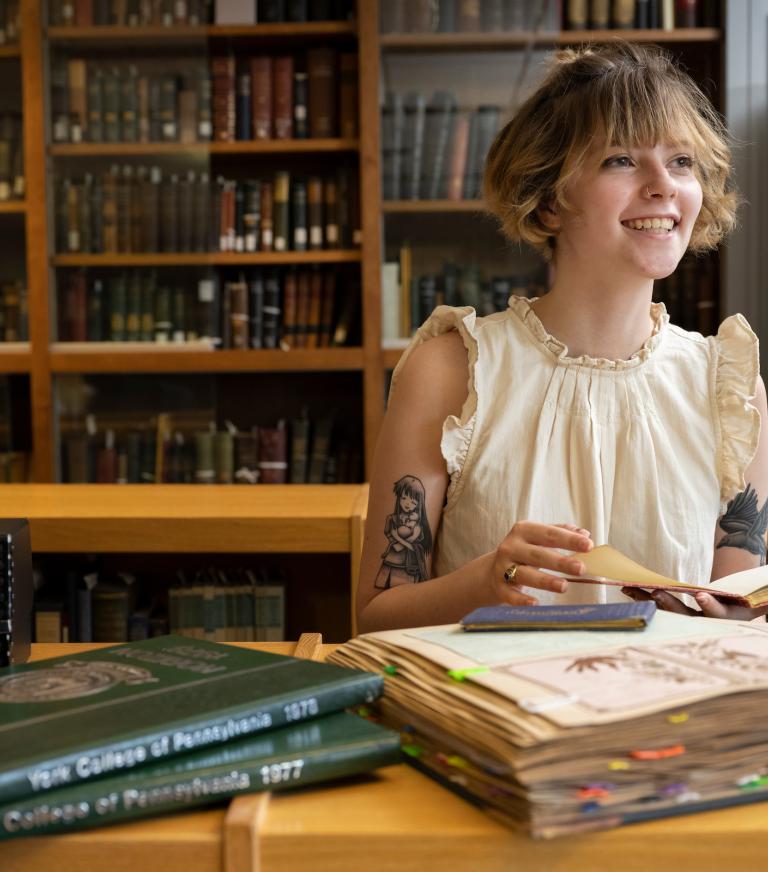 A student in the library with books.